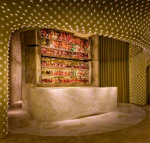 A dimly lit bar with a marble bar and a visually appealing display of liquor bottles