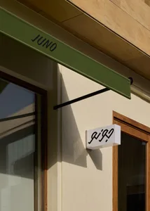 一張城市門面店鋪的照片，店面上有綠色遮陽棚和白色招牌，背景是典型的城市環境的木質外牆