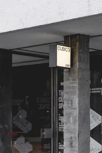 Black and white photograph of a traditional commercial building with a brick exterior and a white sign with black lettering on a stone wall