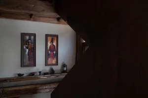 Cozy living space with a wooden floor, wooden staircase, and rustic decor, featuring a painting and decorative items on a shelf