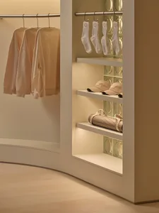 A well-organized closet with a white shelf and wall, featuring various clothing items and a focus on storage and organization
