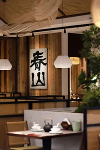 A modern restaurant interior with wooden panel walls, well-lit and inviting, featuring tables and chairs for social dining