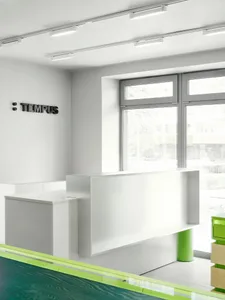 A well-lit office space with a white desk, counter, and chair, featuring a predominantly white color scheme and modern aesthetic