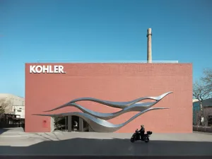 Photograph of a pink building with a large metallic sculpture and a modern, artistic design