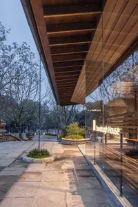 Photograph of a modern building with a large glass wall and metal roof, showcasing its sleek and contemporary design