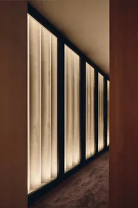 A modern residential hallway with glass windows, wood walls, and natural light, creating a bright and welcoming atmosphere