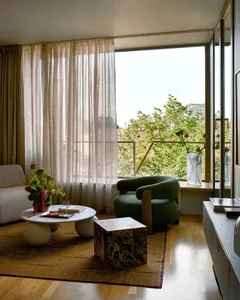 Comfortable living space with a couch, chair, dining table, and vases, featuring wood and glass materials, well-lit for a warm atmosphere