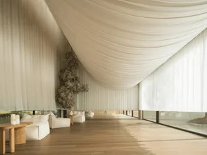 A large, open room with a wooden floor, featuring a variety of furniture and decorative elements, including chairs, a dining table, and potted plants, creating an inviting and comfortable atmosphere