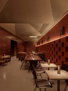 A warm and inviting dining area with a long wooden table surrounded by chairs, set with wine glasses, cups, and a vase, creating a cozy atmosphere