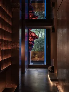 Cozy modern room with a stone wall, glass door, and natural light, featuring a bench and chair in a brown and blue color scheme