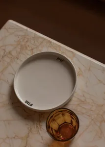 A white plate sits on a marble table in a dining room setting, creating a clean and elegant atmosphere