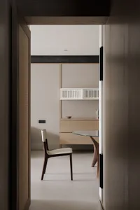 A modern kitchen with a white countertop, glass table, and a chair, set in a dimly lit space