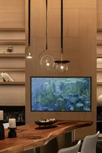 A modern living room with wooden walls and a wooden table, featuring a flat screen TV, books, and a bowl, with balanced lighting creating a comfortable atmosphere