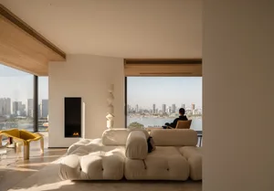 A modern living room with a white couch, a chair, and a fireplace, featuring clean lines and minimalistic design elements, with natural light streaming in through the windows