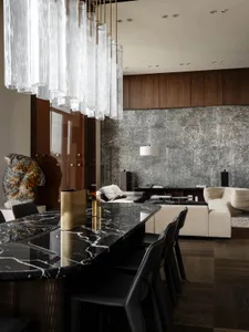 Cozy modern living room with a black marble countertop, a wooden floor, and a gold vase on display, featuring a couch, chair, and dining table