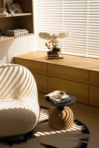A well-lit living room with a white chair and wooden cabinet, creating a bright and inviting atmosphere