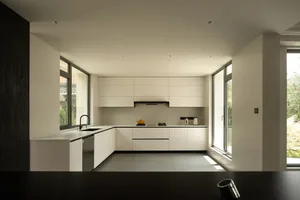 A modern kitchen with white cabinets, a black countertop, and dim lighting creating a cozy atmosphere