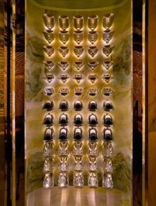 A modern wall with a row of metal light fixtures mounted at different heights, set against a marble background