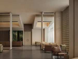A modern lobby with several chairs arranged for conversation, near a large window with natural light and a clean, minimalist design