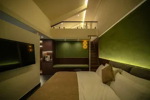 Cozy bedroom with a bed, television, and staircase, decorated in green and white, with a modern and inviting atmosphere