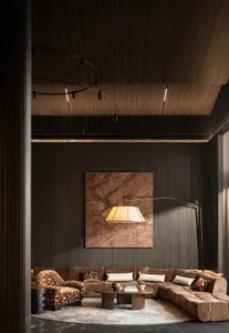 A dimly lit living room with a brown couch and chair, wooden floor, and brown and white color scheme, creating a cozy atmosphere for conversation and relaxation