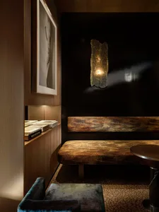 一間舒適的坐姿區域中有座著一張木制長椅，靠著一面黑色牆壁，營造出溫暖和親密的氛圍