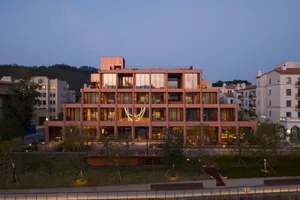 A large, multi-story building with a pink facade, featuring a mix of architectural styles, wood, and glass, and natural light streaming in through the windows