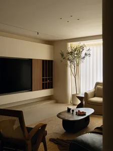 Comfortable living space with a flat screen TV, couch, chair, coffee table, and potted plant, well-lit and inviting