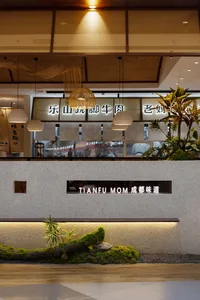 A bright and welcoming restaurant with a large window, potted plants, a dining table, and decorative elements in a modern and minimalist space