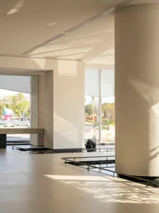 Open modern living and dining space with a white wall, black counter, and large window, well-lit by natural light