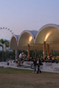 A modern building with a large white dome, set against a dimly lit background, featuring a concrete facade and metal dome