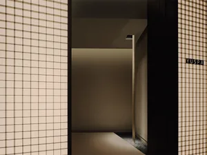 Dimly lit residential hallway with an open doorway and a light fixture on the wall