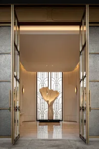 Ornate doorway with a glass door featuring a wooden carved tree in a white interior setting with soft and diffused lighting