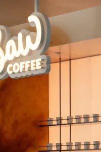A modern coffee shop with a sleek counter, neon sign, and rows of cups in various positions, set in a welcoming atmosphere