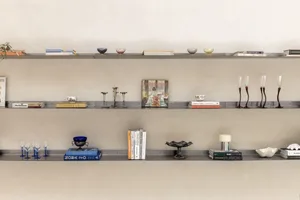A cozy bookshelf filled with various books and decorative items, including vases, against a wall in a personal space
