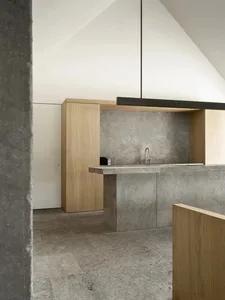 Modern kitchen with a gray concrete countertop, empty space, and dim lighting
