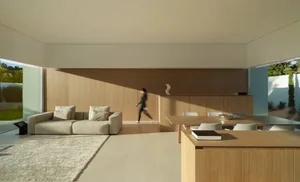 A woman walks towards a dining table in a well-lit living room with a couch and chair