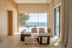 海岸線生活室，擁有大窗戶俯瞰大海的景色，featuring couch、椅子和咖啡桌，採用現代化風格和中性顏色調