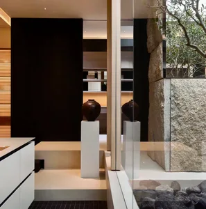 Bathroom with a black and white color scheme, featuring a sink, toilet, and mirror, with stone wall and dim lighting