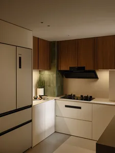 Modern kitchen with white cabinets, black stove, and a potted plant on the countertop, set against a dimly lit background