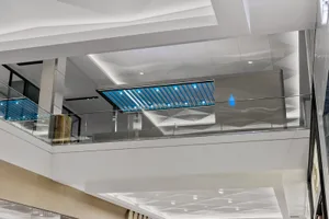 Large, open lobby with a blue and white color scheme, a glass ceiling, and a prominent blue bar, creating a welcoming and inviting atmosphere