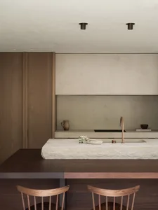 A well-lit modern kitchen with a stone countertop and metal sink, creating a warm and inviting atmosphere