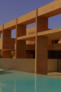 A modern house with a swimming pool surrounded by a stone wall, featuring a unique design with brown and orange colors, creating a relaxing and inviting atmosphere