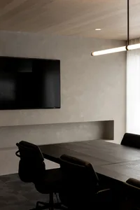 A black and white photograph of a cozy living room with a wooden table and two chairs, a flat screen TV on the wall, and a timeless classic atmosphere