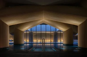 A relaxing pool area with a wooden ceiling, surrounded by a wooden deck and potted plants, with a calm atmosphere