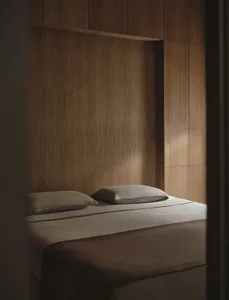 Cozy bedroom with a brown wooden wall, a white bed, and natural soft lighting