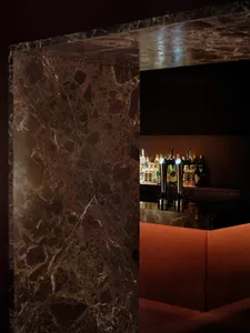 A modern bar with a marble countertop featuring various bottles arranged in a visually appealing way, set in a well-lit environment