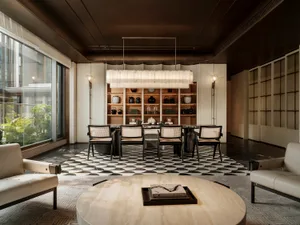 Dining room with a large wooden table and chairs, surrounded by various decorative items, with a large window allowing natural light to fill the space