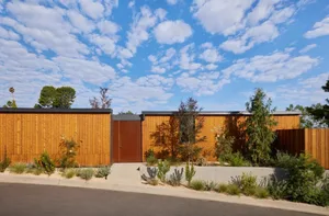A traditional house with a wooden exterior, surrounded by a garden with trees and bushes, creating a serene and natural atmosphere