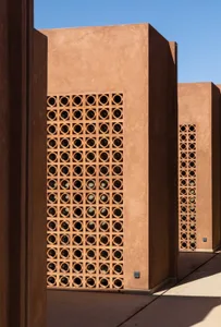 Photograph of a brown brick building with a unique patterned wall and small windows, taken during the daytime with natural light